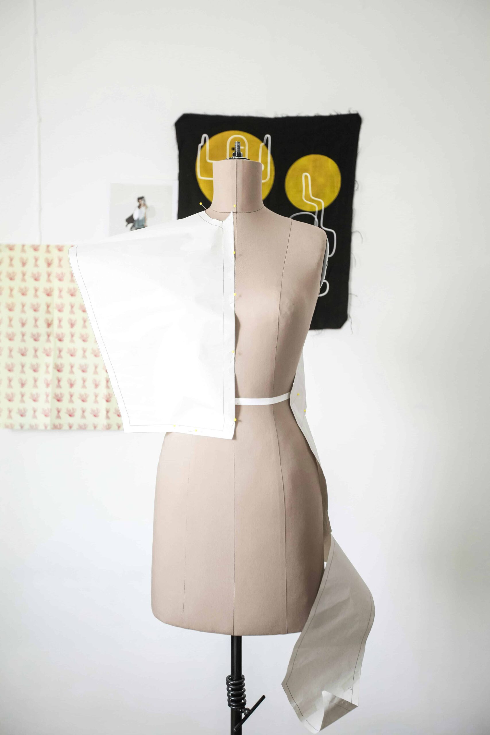 White dress form with fabric being draped and pinned for pattern development